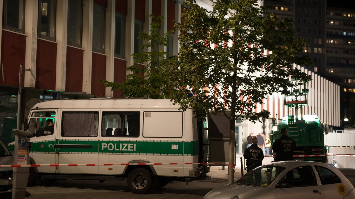 Einsatzfahrzeuge der Polizei stehen in Berlin-Mitte am Abend vor einer Absperrung. Dort wurde auf einem Platz nahe einem Hochhaus eine Leiche gefunden. Ein Zelt wurde über den Fundort gestellt, bevor die Kriminaltechniker ihre Arbeit aufnahmen.