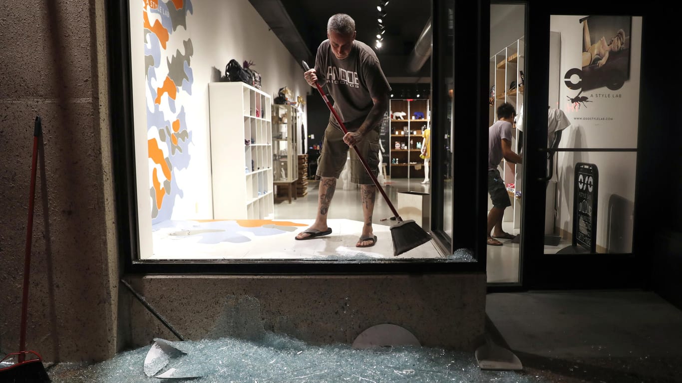 Scott McRoberts räumt nach einer gewalttätigen Demonstration die Scherben eines zerbrochenen Schaufensters weg.