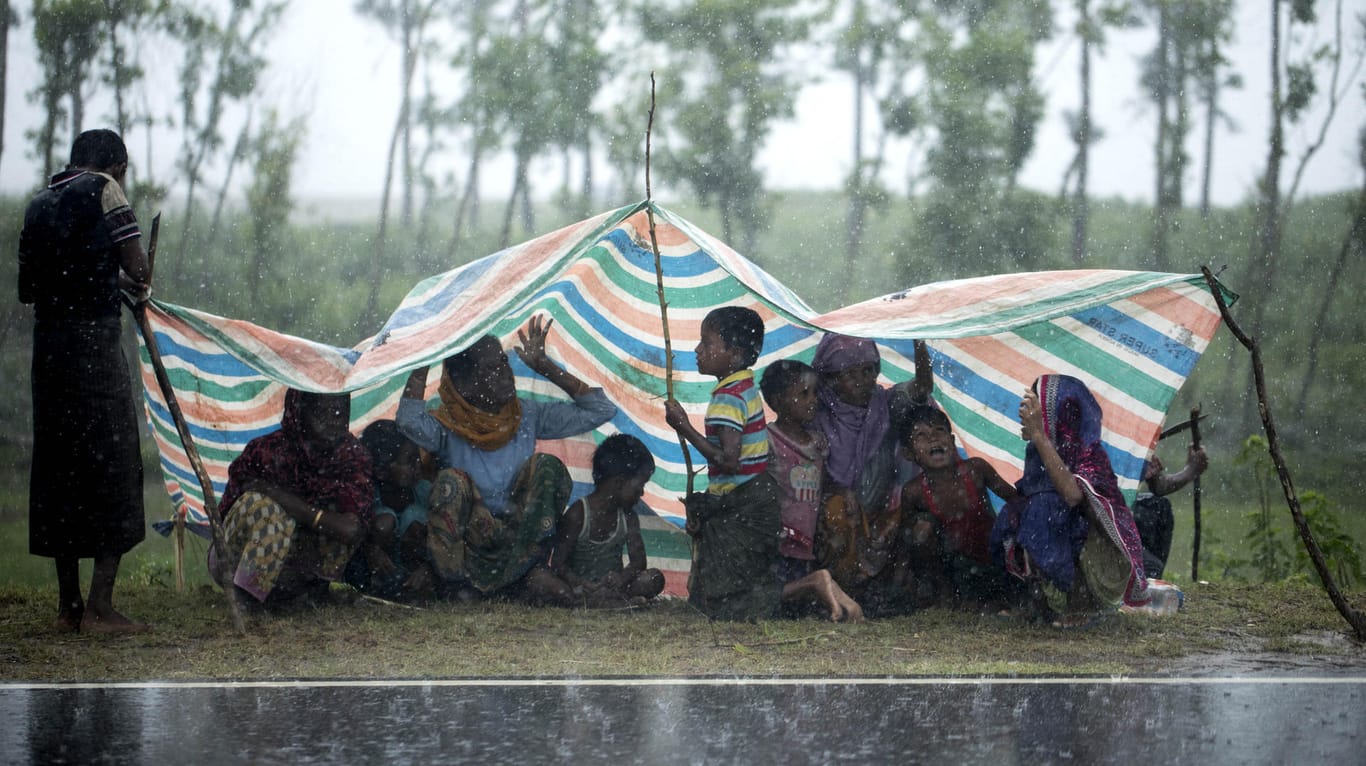 Rohingya-Flüchtlinge aus Myanmar sitzen in Cox's Bazar unter einer Plastikplane, um sich vor dem Regen zu schützen.