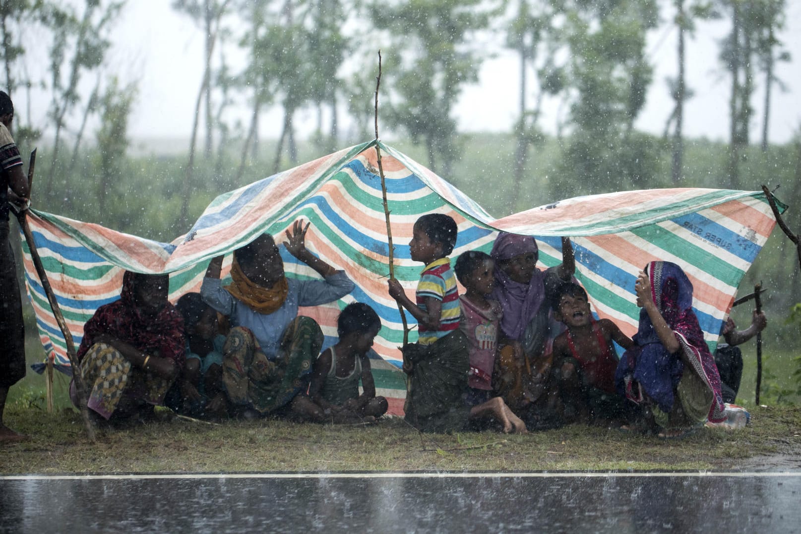 Rohingya-Flüchtlinge aus Myanmar sitzen in Cox's Bazar unter einer Plastikplane, um sich vor dem Regen zu schützen.