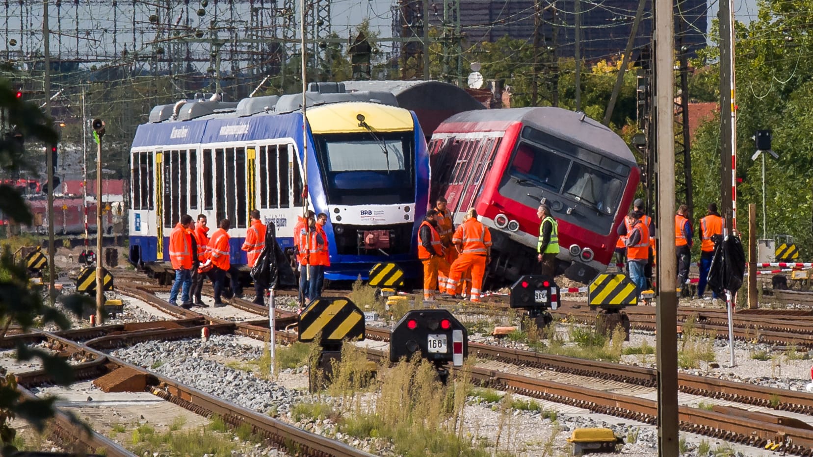 Diverse Mitarbeiter der Bahn stehen in Augsburg neben einem verunglücktem Personenzug.