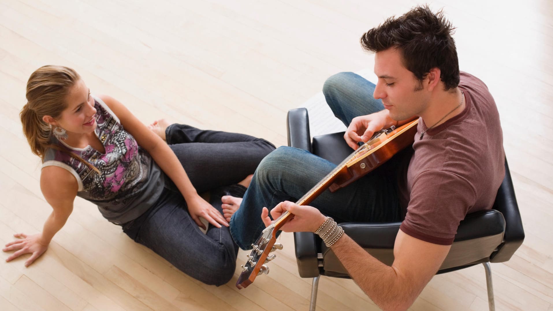 Frau hört Mann zu, der Gitarre spielt