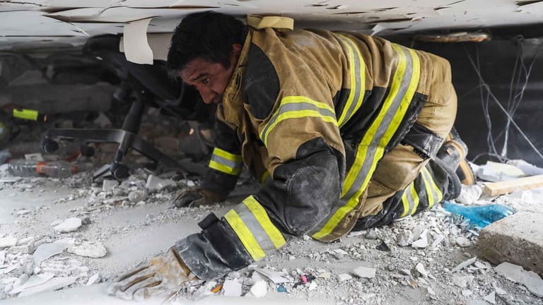 Ein Feuerwehrmann sucht in Mexiko-Stadt in einem zerstörten Gebäude nach Überlebenden des Erdbebens.