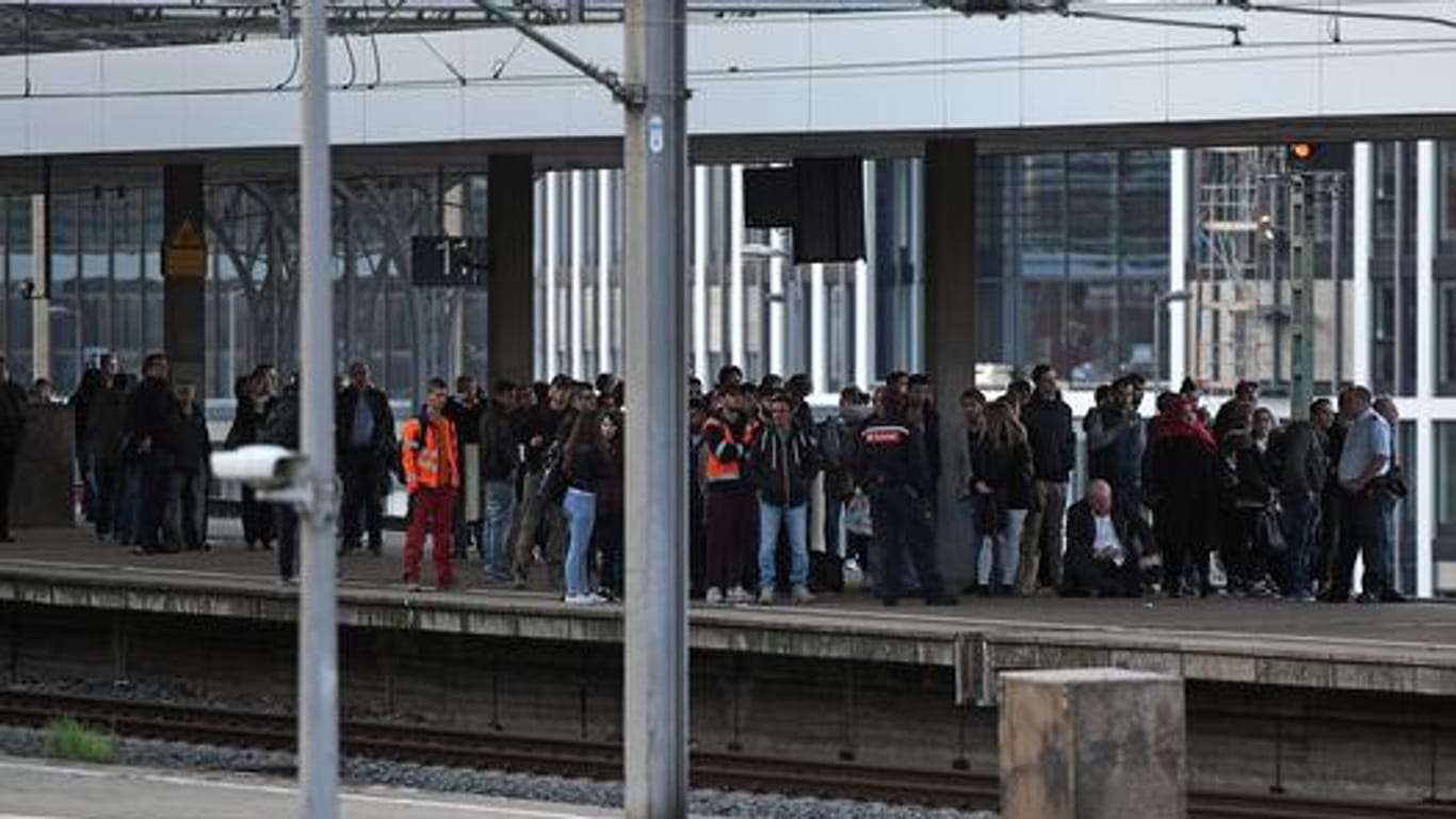 Fahrgäste warten am Kölner Hauptbahnhof auf ihren Zug. Die Hohenzollernbrücke musste wegen eines Mannes, der auf die Bögen der Brücke geklettert war, gesperrt werden.