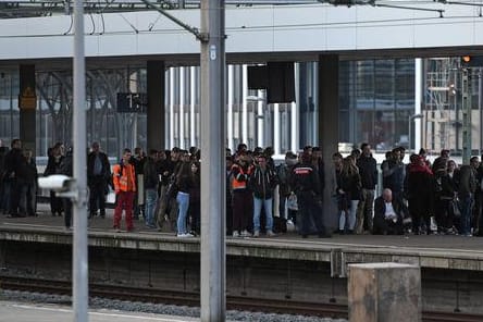 Fahrgäste warten am Kölner Hauptbahnhof auf ihren Zug. Die Hohenzollernbrücke musste wegen eines Mannes, der auf die Bögen der Brücke geklettert war, gesperrt werden.