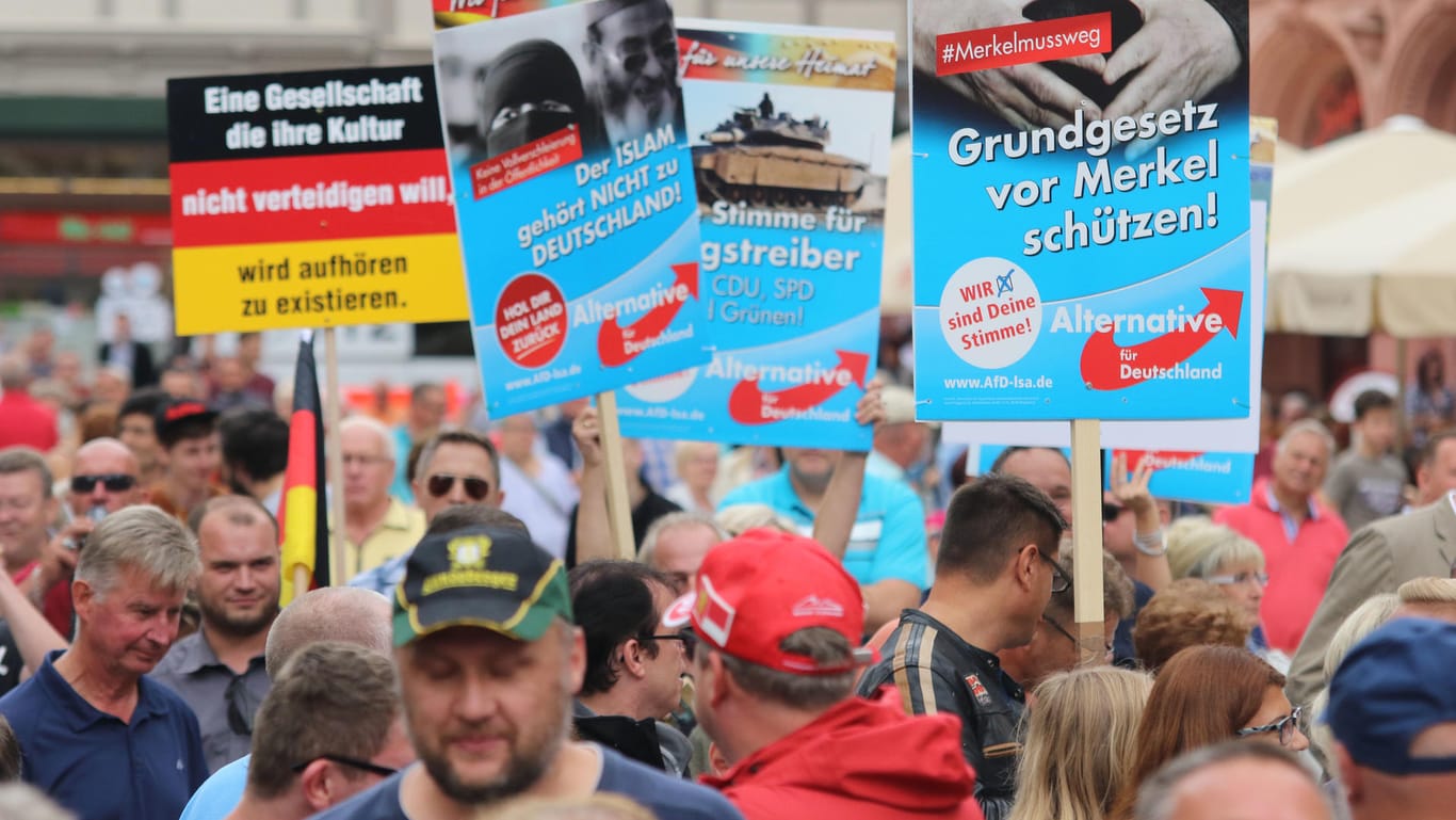 Demonstranten halten am Rande einer Wahlkampfveranstaltung der CDU mit Bundeskanzlerin Merkel auf dem Marktplatz in Quedlinburg Plakate der AfD hoch.