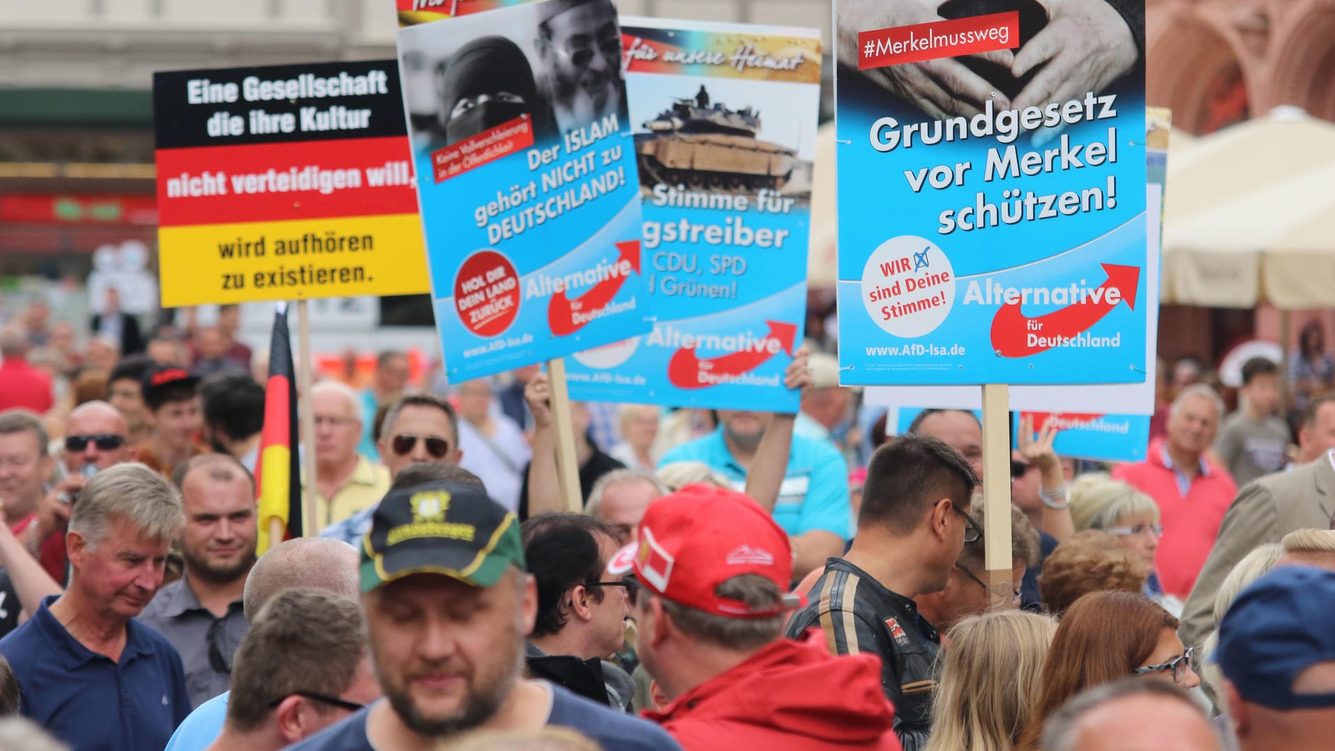 Demonstranten halten am Rande einer Wahlkampfveranstaltung der CDU mit Bundeskanzlerin Merkel auf dem Marktplatz in Quedlinburg Plakate der AfD hoch. Demonstranten halten am Rande einer Wahlkampfveranstaltung der CDU mit Bundeskanzlerin Merkel auf dem Marktplatz in Quedlinburg Plakate der AfD hoch.