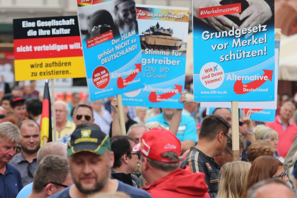Demonstranten halten am Rande einer Wahlkampfveranstaltung der CDU mit Bundeskanzlerin Merkel auf dem Marktplatz in Quedlinburg Plakate der AfD hoch.