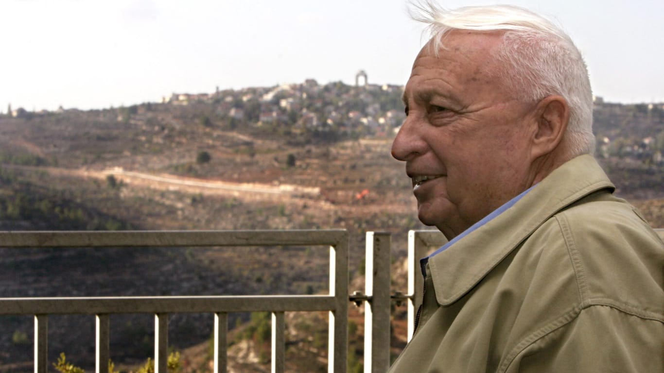 In der Siedlung Har Adar im Westjordanland hat ein palästinensischer Angreifer drei Israelis erschossen. Das Foto zeigt den früheren Premierminister Israels im Jahr 2005, im Hintergrund ist die Ortschaft Har Adar zu sehen.