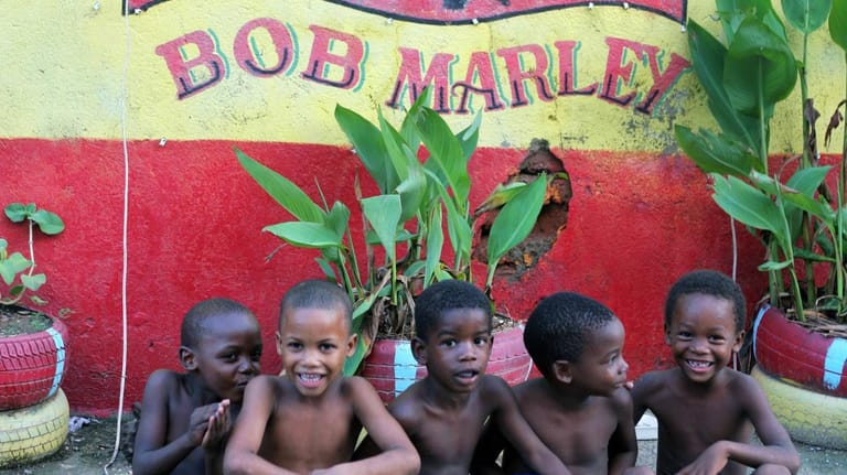 Kinder im Armenviertel Southsite unter einem Bild der Musikerlegende Bob Marley in Kingston.