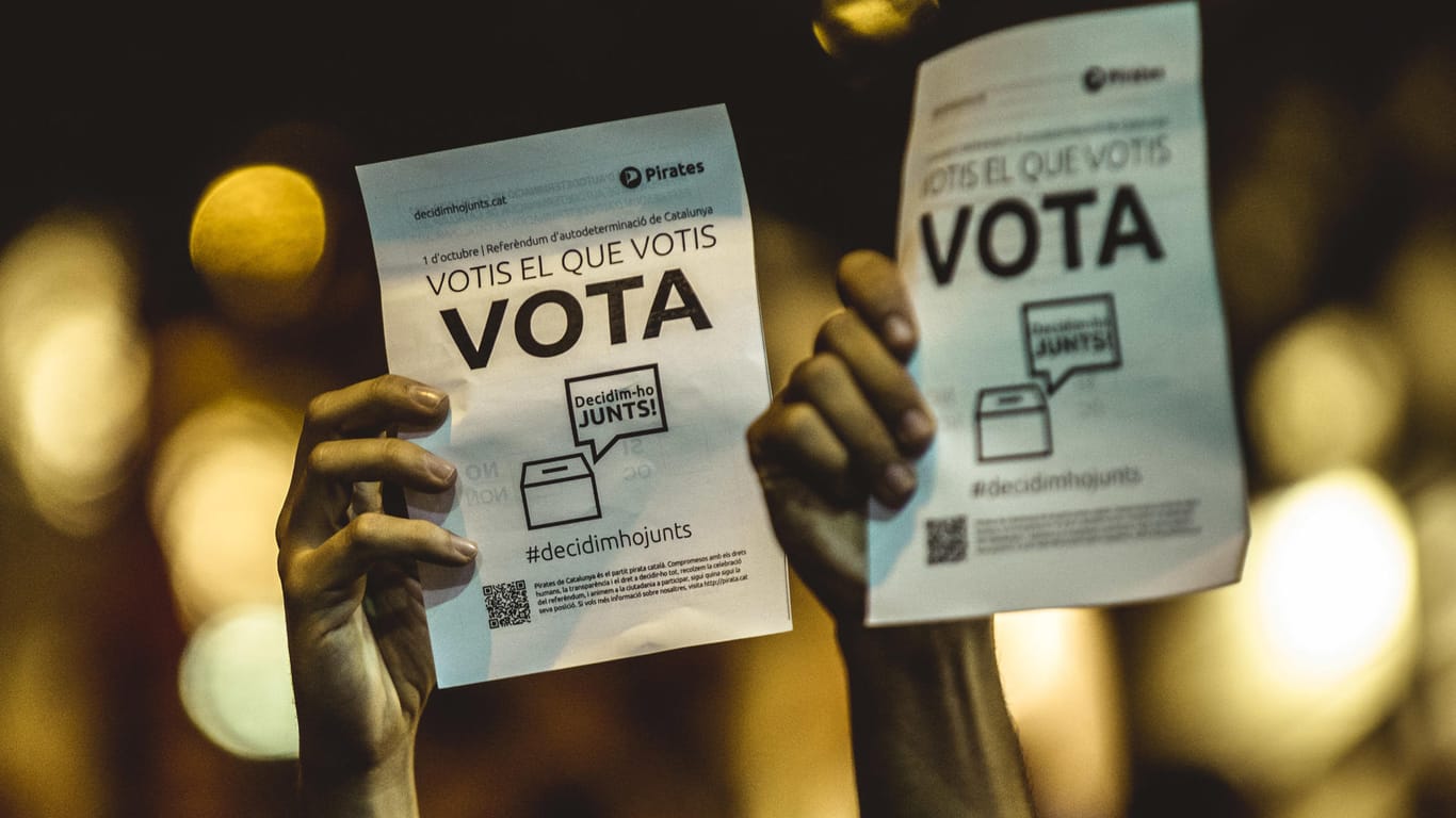 Katalanische Demonstranten halten Wahlzettel hoch.
