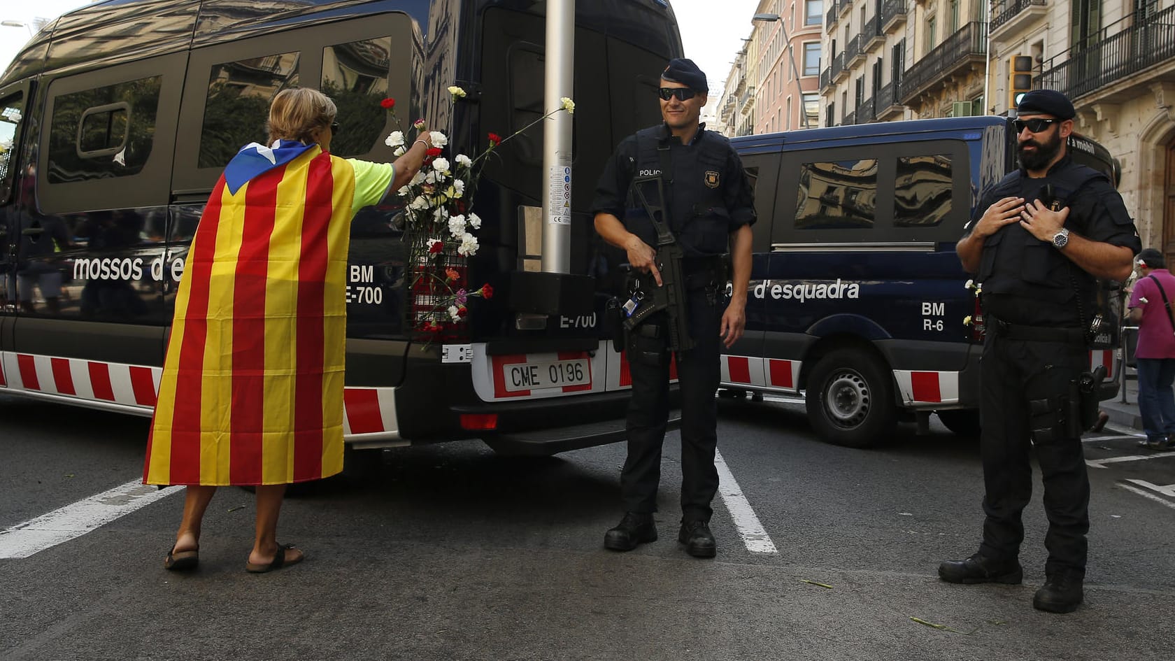 Ein Frau mit einer "Estelada"-Flagge steckt Nelken an einen Polizeiwagen.
