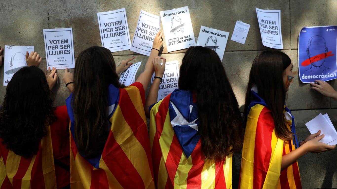 Junge Frauen mit katalonischen Flaggen kleben in Barcelona Aufrufe für das Unabhängigkeits-Referendum mit der Aufschrift "Wir wählen um frei zu sein" an eine Wand.