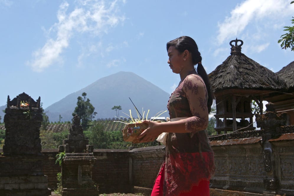 Ein Balinesin bringt in Karangasem (Indonesien) Opfergaben in einen Tempel der 10 Kilometer des Vulkans Mount Agung entfernt liegt. Auf der indonesischen Ferieninsel Bali wächst die Furcht vor einem gewaltigen Vulkanausbruch.