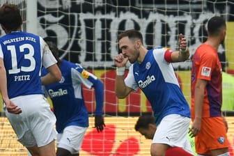 Kiel-Kapitän Rafael Czichos (m.) feiert seinen Treffer zum 2:0 mit Babyjubel.