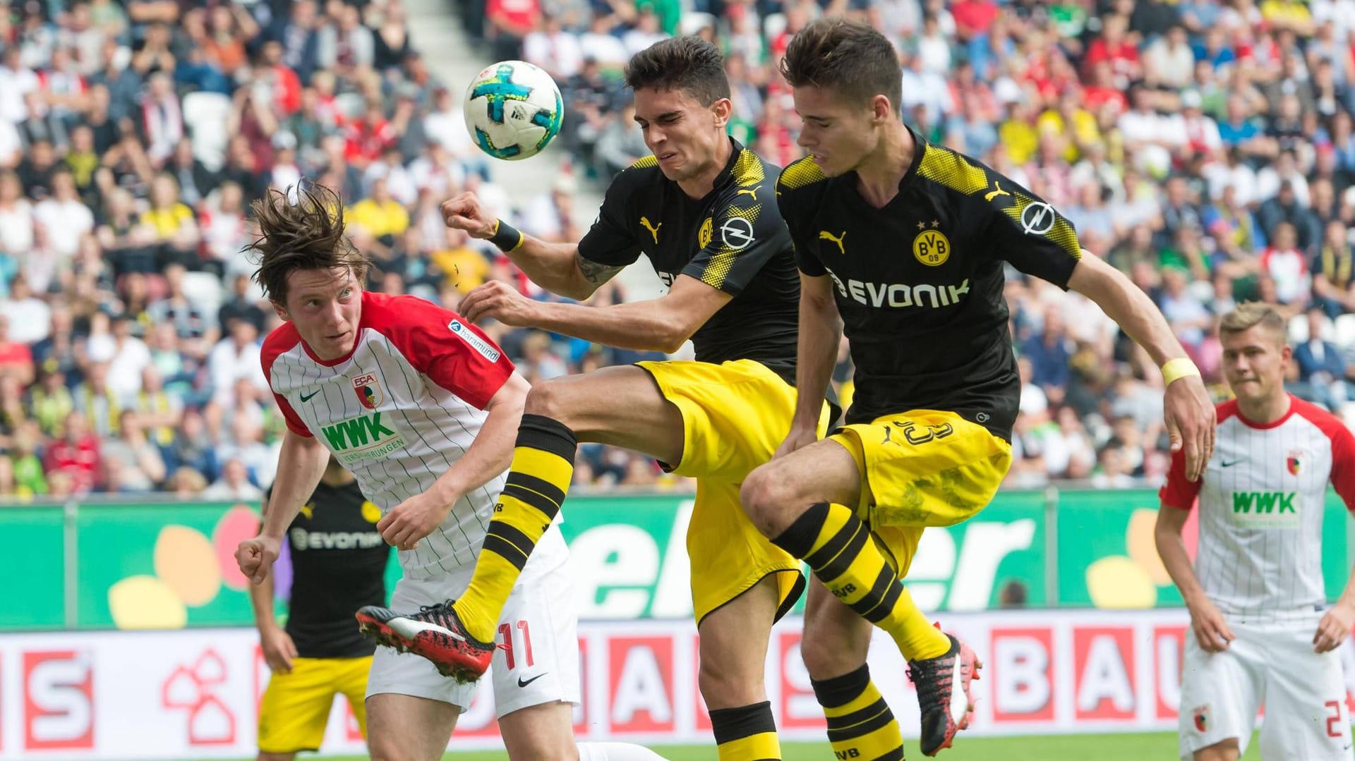 Dortmunds Julian Weigl (v. r.) und Marc Bartra wollen den Kopfball von Augsburgs Michael Gregoritsch stoppen. Dortmunds Julian Weigl (v. r.) und Marc Bartra wollen den Kopfball von Augsburgs Michael Gregoritsch stoppen.