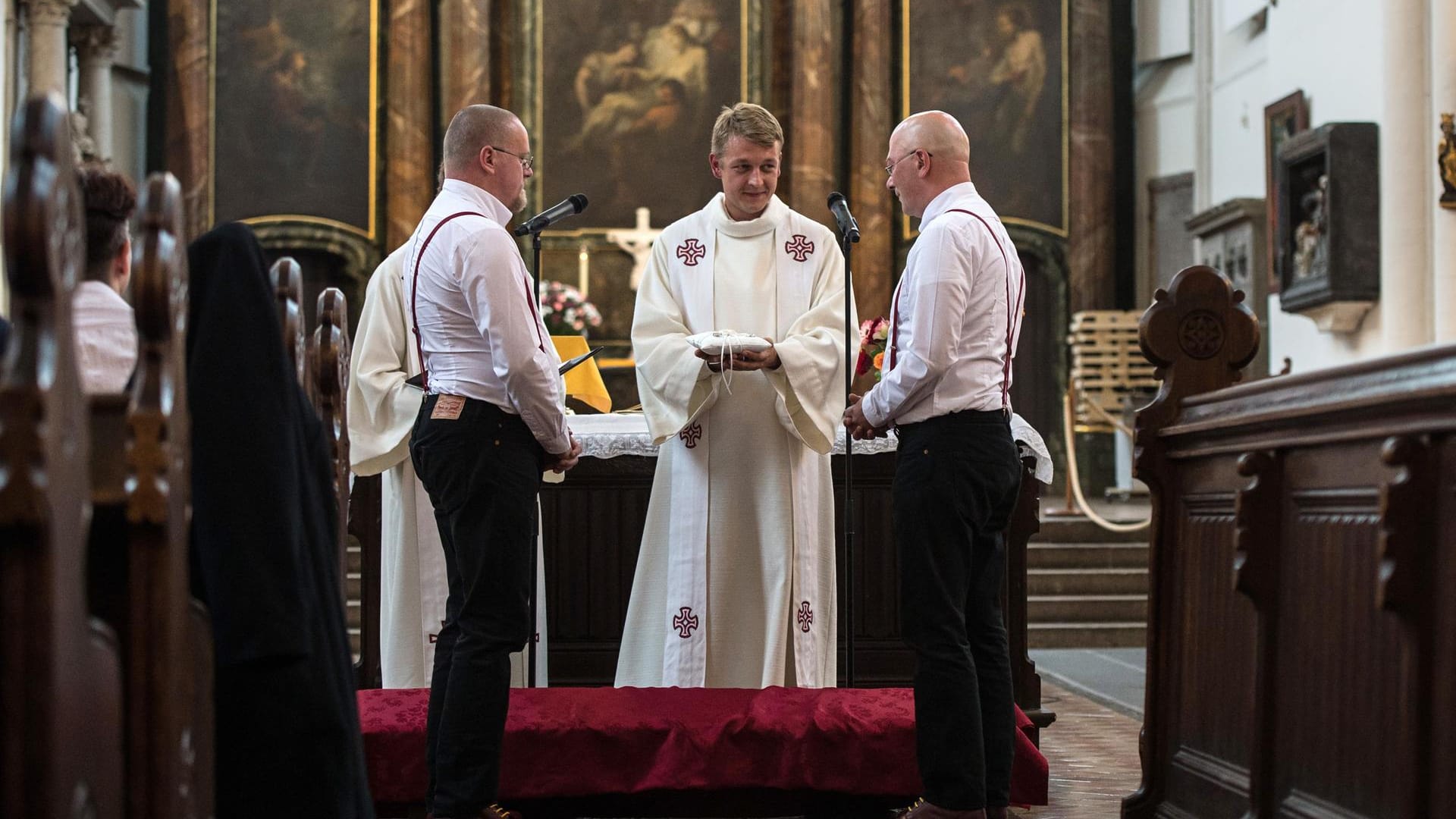 Sven Kretschmer (l) und Tim Schmidt-Kretschmer stehen beim Ringtausch bei der Trauung am 12.08.2016 in der Marienkirche in Berlin vor Pfarrer Eric Haußmann.