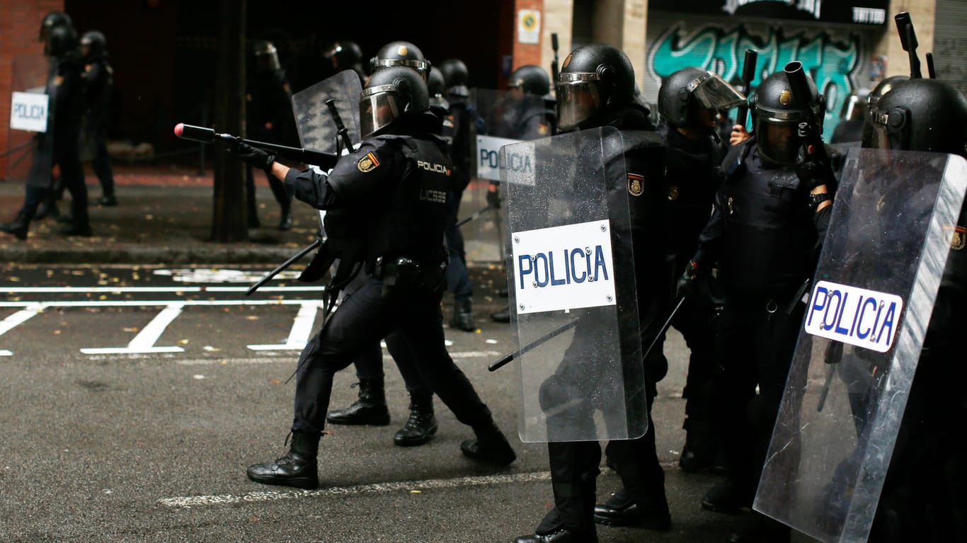 Ein spanischer Polizist zielt mit einem Gummigeschoss auf Demonstranten in Barcelona.