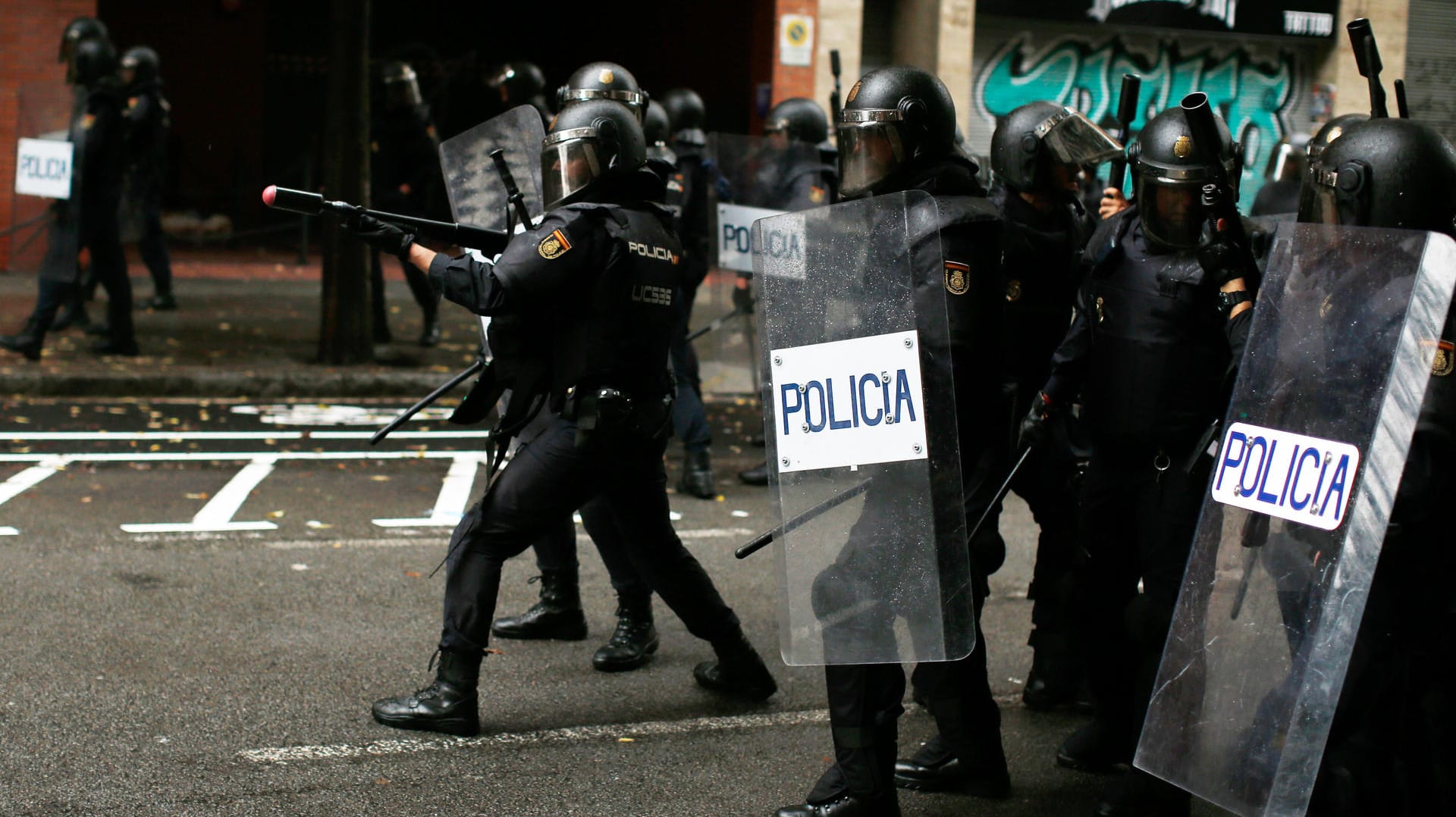 Ein spanischer Polizist zielt mit einem Gummigeschoss auf Demonstranten in Barcelona. Ein spanischer Polizist zielt mit einem Gummigeschoss auf Demonstranten in Barcelona.