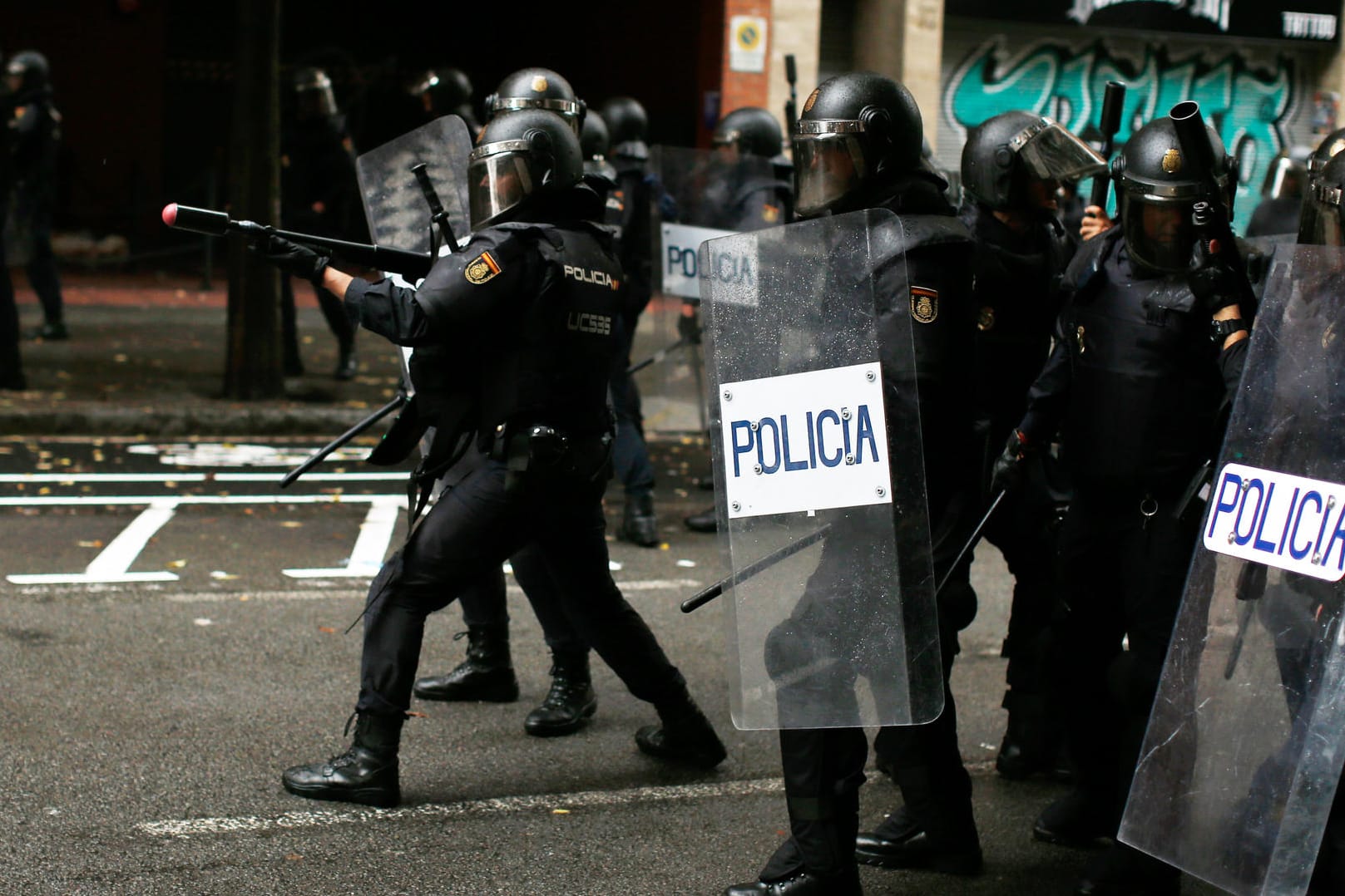 Ein spanischer Polizist zielt mit einem Gummigeschoss auf Demonstranten in Barcelona.