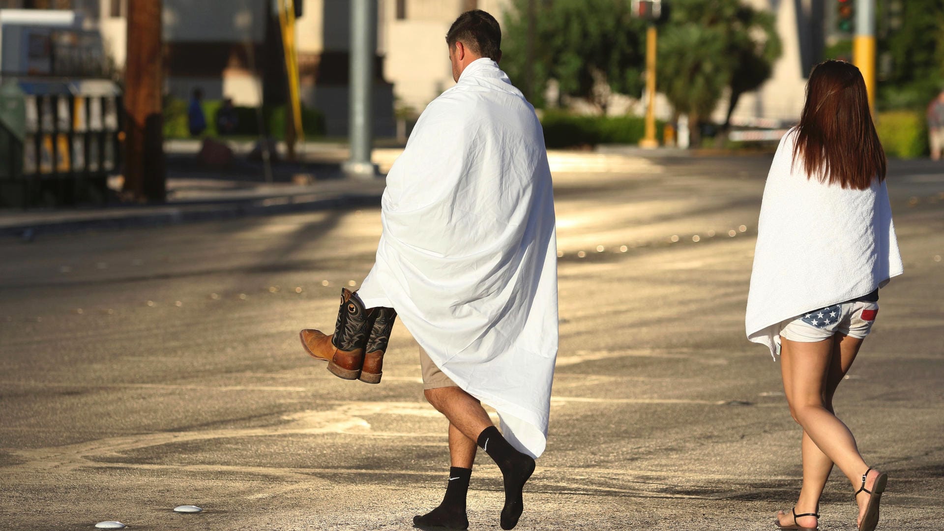 In Decken gehüllt gehen zwei Menschen bei Sonnenaufgang nahe des Las Vegas Strip in der Kasino-Stadt die Straße entlang.