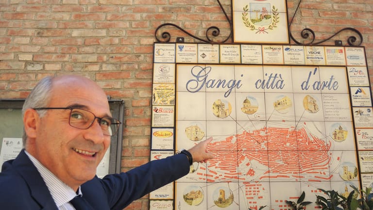 Der Bürgermeister der sizilianischen Gemeinde Gangi, Francesco Paolo Migliazzo, zeigt auf Kacheln, die das Stadtbild Gangis zeigen.