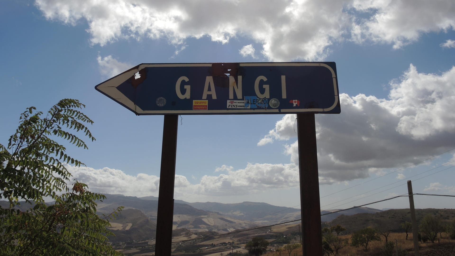 Blick auf ein Straßenschild, das in den sizilianischen Ort Gangi führt. Der Hintergrund läst einen wunderschönen Panorama-Blick erahnen.