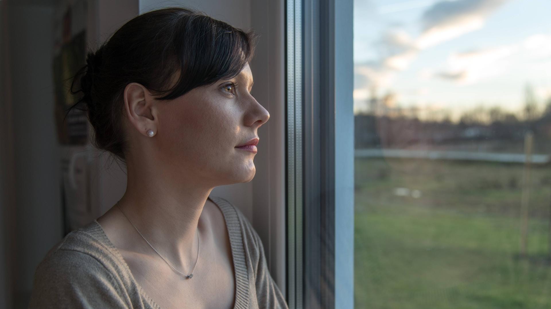 Frau schaut aus dem Fenster: Vor allem Müttern fällt das Loslassen schwer.