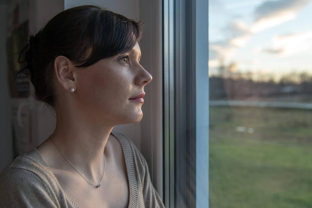 Frau schaut aus dem Fenster: Vor allem Müttern fällt das Loslassen schwer.