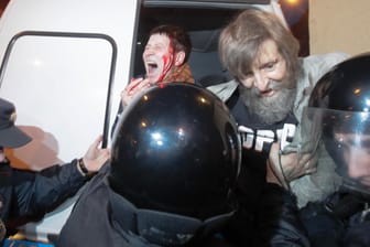 In St. Petersburg führen Polizisten bei Anti-Putin-Protesten eine Frau mit einer blutenden Kopfwunde ab.