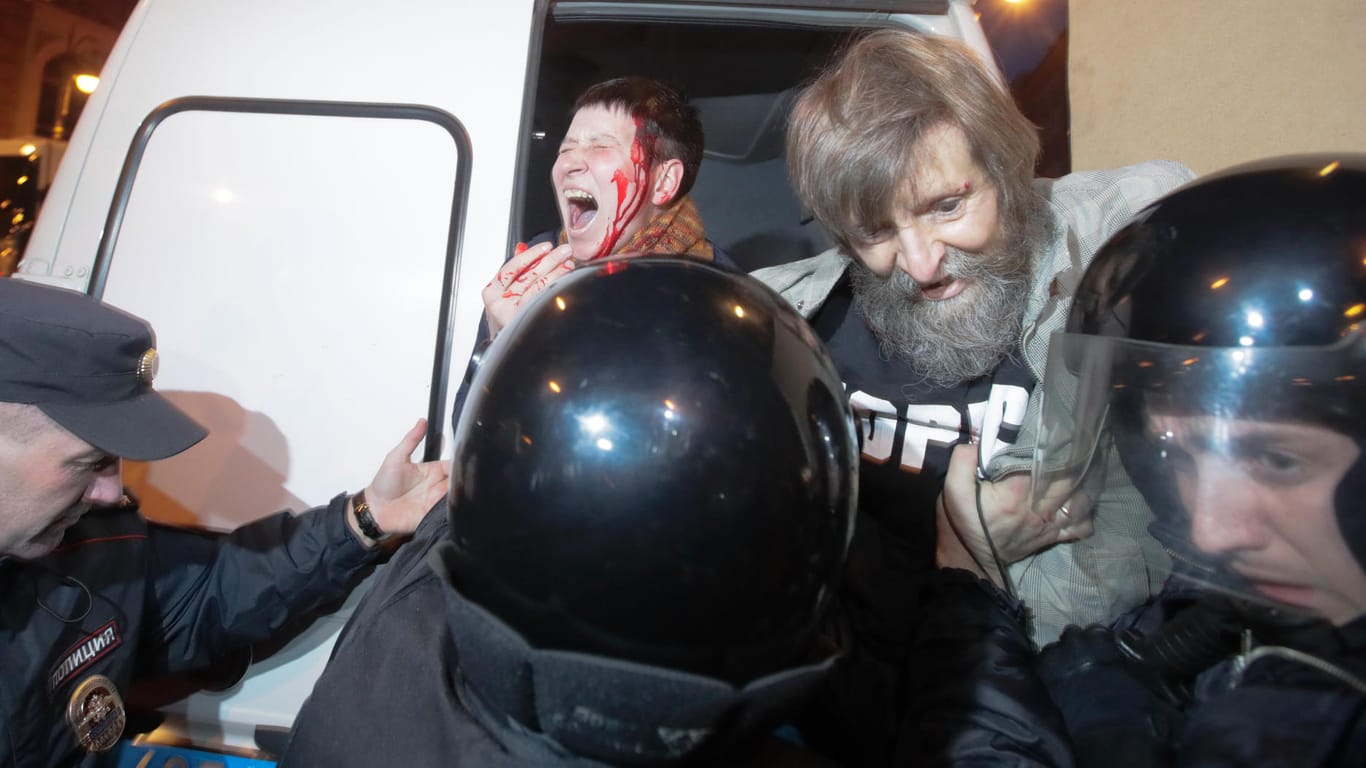 In St. Petersburg führen Polizisten bei Anti-Putin-Protesten eine Frau mit einer blutenden Kopfwunde ab.