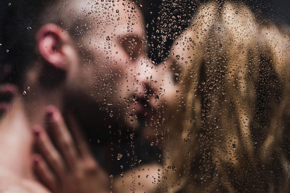Ein Mann und eine Frau küssen sich unter der Dusche