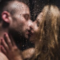 Ein Mann und eine Frau küssen sich unter der Dusche