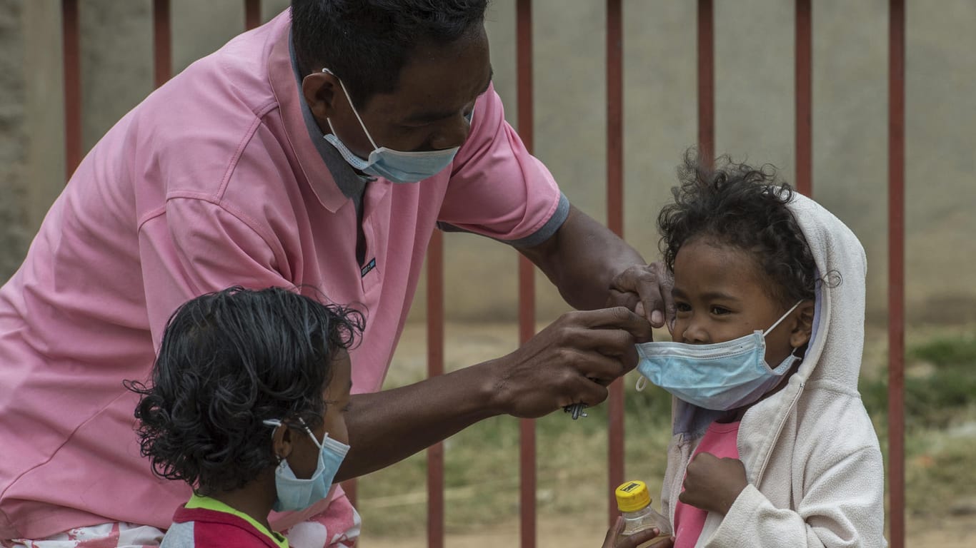 Ein Mann hilft am in Antananarivo, der Hauptstadt Madagaskars, einem Kind beim Anlegen eines Mundschutzes. Immer mehr Menschen infizieren sich auf Madagaskar mit der lebensgefährlichen Lungenpest.