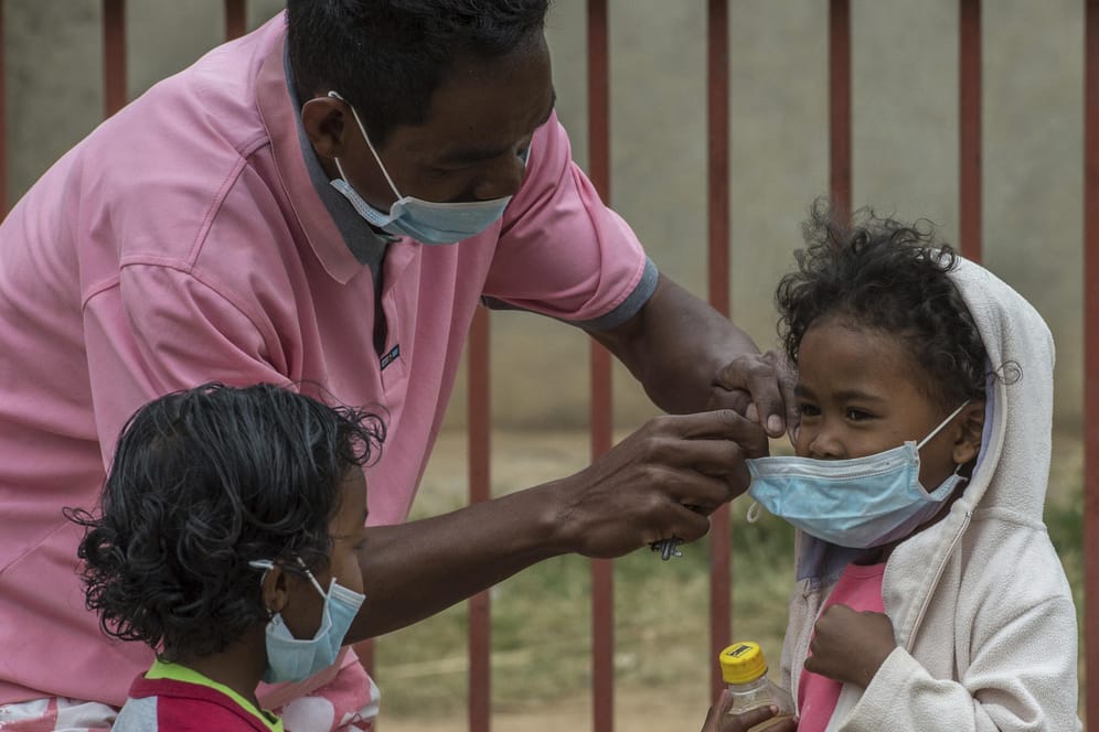 Ein Mann hilft am in Antananarivo, der Hauptstadt Madagaskars, einem Kind beim Anlegen eines Mundschutzes. Immer mehr Menschen infizieren sich auf Madagaskar mit der lebensgefährlichen Lungenpest.