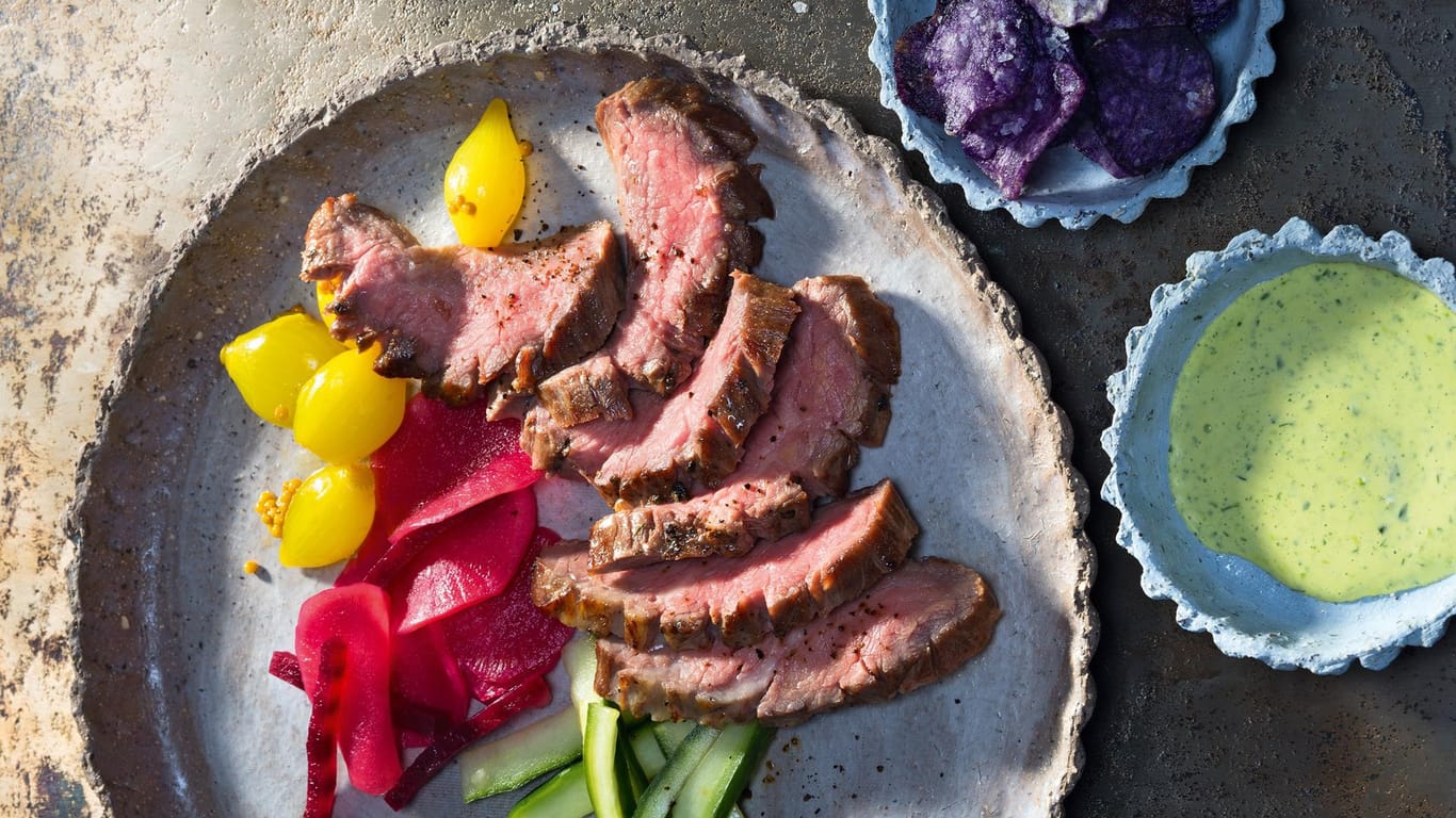 Rindersteak-Streifen mit eingelegtem Gemüse, Blaukartoffel-Chips und Petersilie-Mayonnaise wurden für ein Foto schmackhaft angerichtet.