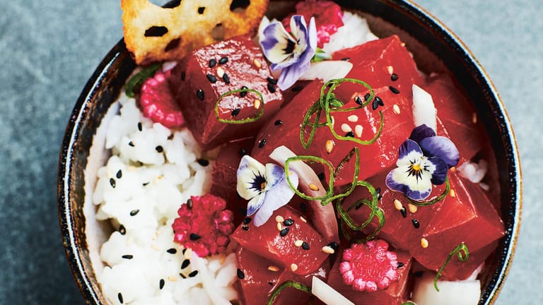 Eine traditionelle Poke-Bowl mit Thunfisch, Reis, frittierter Lotuswurzel, eingelegtem Maiskolben und essbaren Blüten.