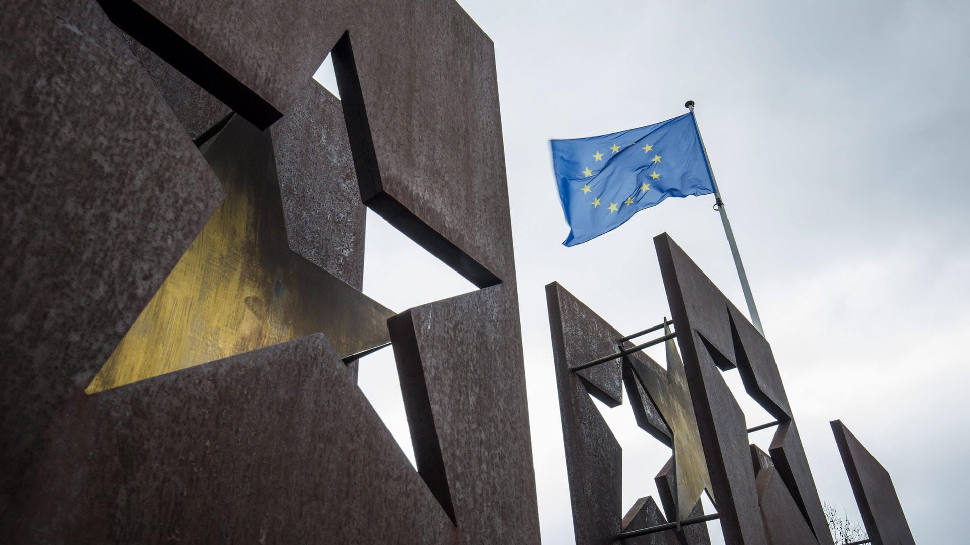 Denkmal für Schengenabkommen, Europafahne weht im Hintergrund Denkmal für Schengenabkommen, Europafahne weht im Hintergrund