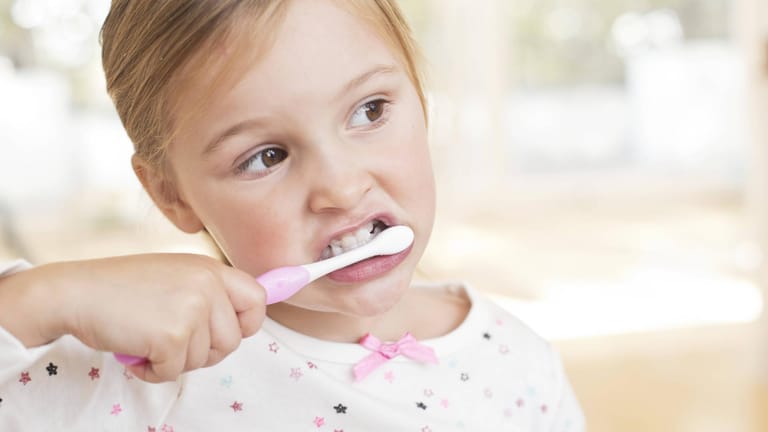 Ein Mädchen putzt seine Zähne: Eltern sollten ihre Kinder zur Hygiene motivieren.