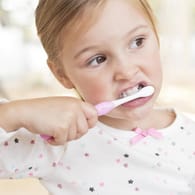 Ein Mädchen putzt seine Zähne: Eltern sollten ihre Kinder zur Hygiene motivieren.