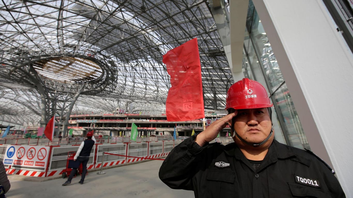 Ein Securitymitarbeiter salutiert im Bau der Terminalhalle des neuen Daxing Airports außerhalb von Peking.