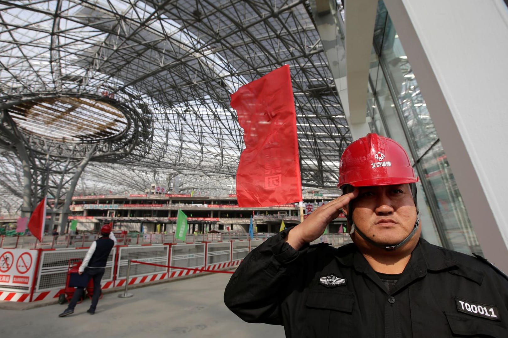 Ein Securitymitarbeiter salutiert im Bau der Terminalhalle des neuen Daxing Airports außerhalb von Peking.