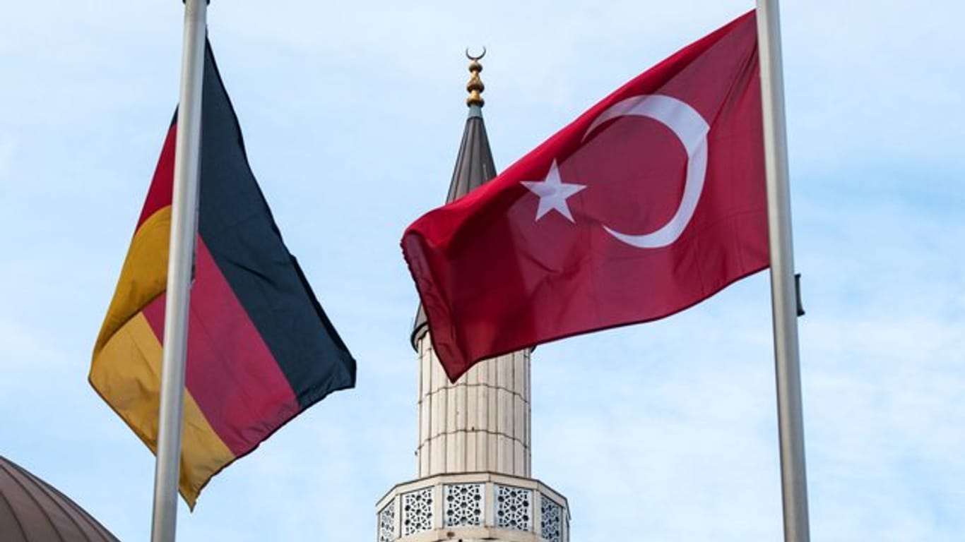 Eine deutsche und eine türkische Fahne wehen in Duisburg-Marxloh vor einer Moschee.