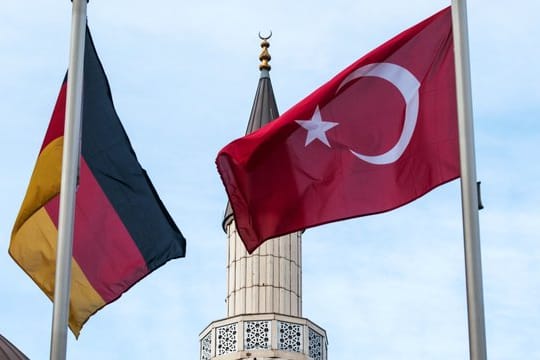 Eine deutsche und eine türkische Fahne wehen in Duisburg-Marxloh vor einer Moschee.