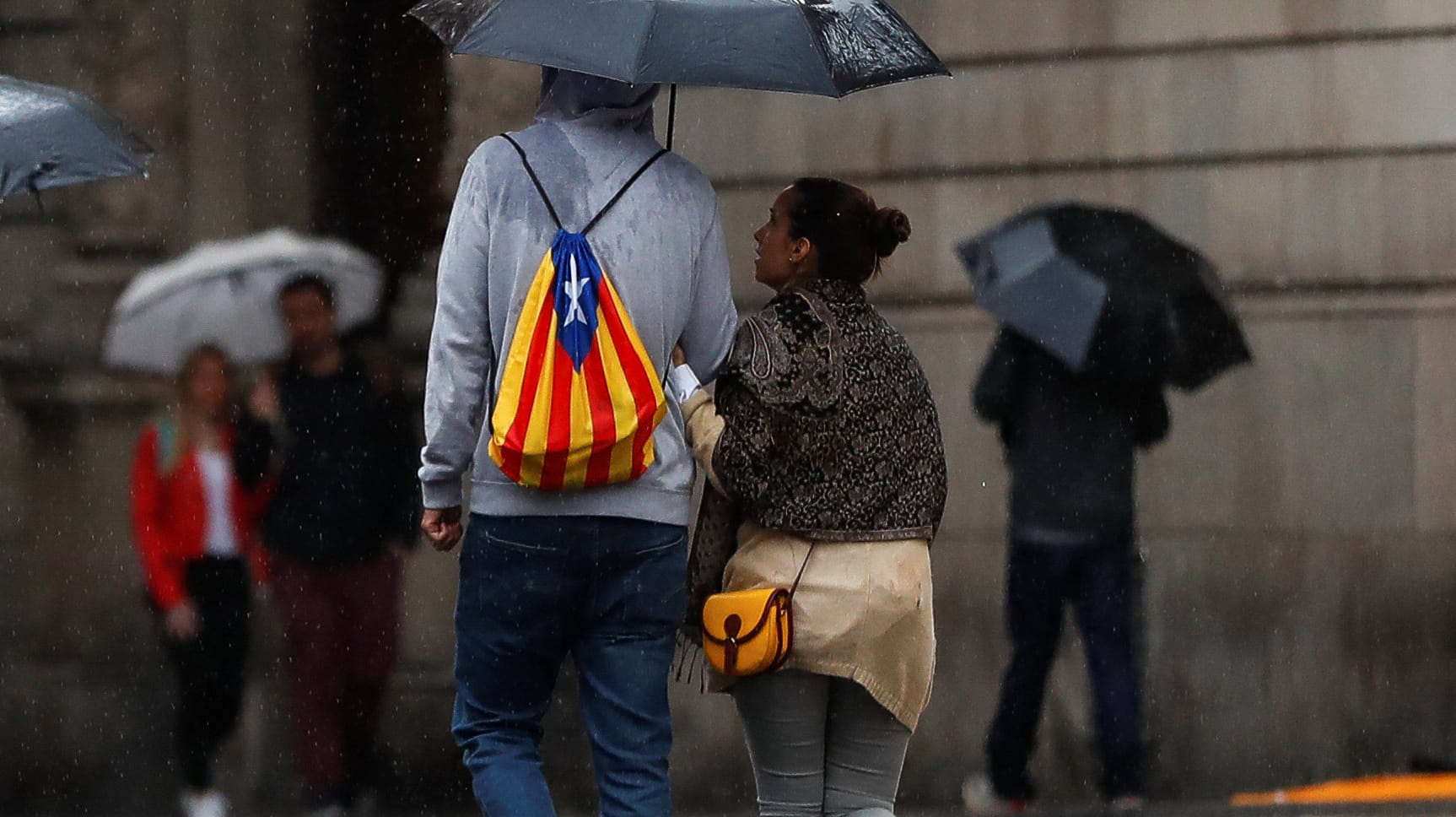 Trübe Aussichten in Barcelona: Ein Mann mit einem Rucksack in den Farben der katalanischen Separatisten läuft durch den Regen. Trübe Aussichten in Barcelona: Ein Mann mit einem Rucksack in den Farben der katalanischen Separatisten läuft durch den Regen.