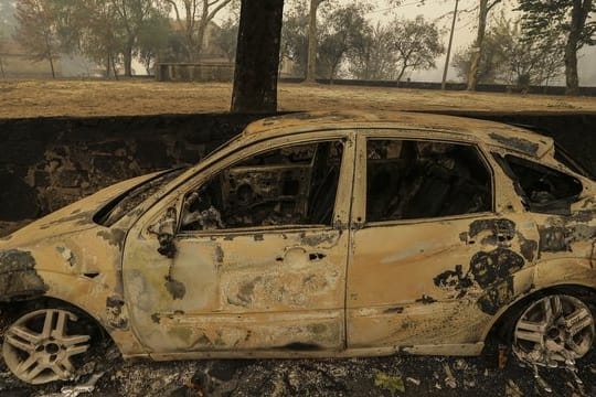 Ein ausgebranntes Auto steht in der Nähe von Vouzela in Portugal auf einer Straße.
