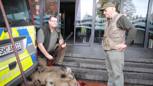 Ein Jäger kniet neben dem von ihn erlegten Wildschwein vor einer Sparkassen-Filiale in Heide. Ein Jäger kniet neben dem von ihn erlegten Wildschwein vor einer Sparkassen-Filiale in Heide.