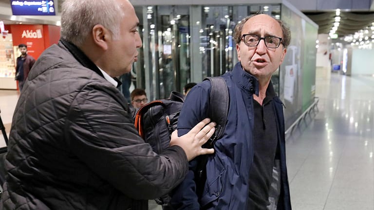 Dogan Akhanli wird in Düsseldorf auf dem Flughafen von seinem Anwalt Illias Uyar festgehalten, nachdem er auf Türkisch beschimpft wurde.