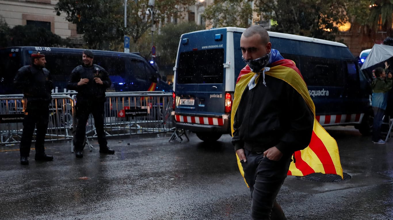 Ein Demonstrant läuft mit einer Flagge der katalonischen Separatisten an einer Polizeisperre vorbei.