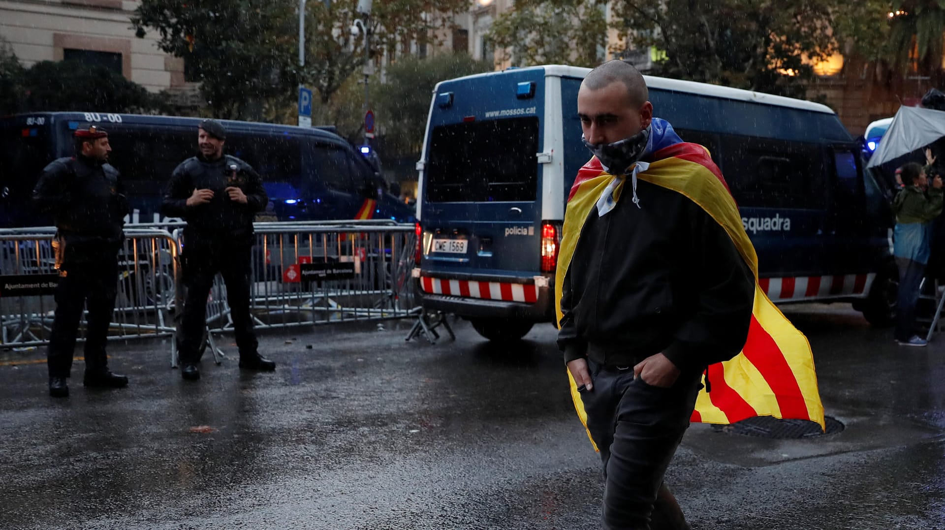 Ein Demonstrant läuft mit einer Flagge der katalonischen Separatisten an einer Polizeisperre vorbei. Ein Demonstrant läuft mit einer Flagge der katalonischen Separatisten an einer Polizeisperre vorbei.